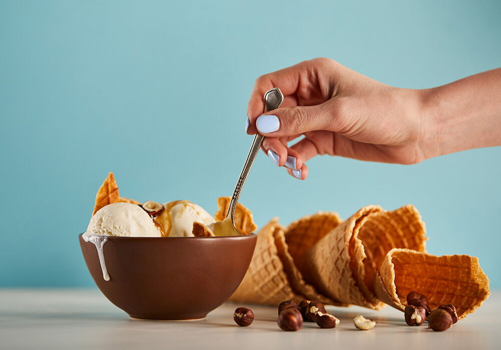Ice cream is eaten by a woman with a spoon from a bowl
