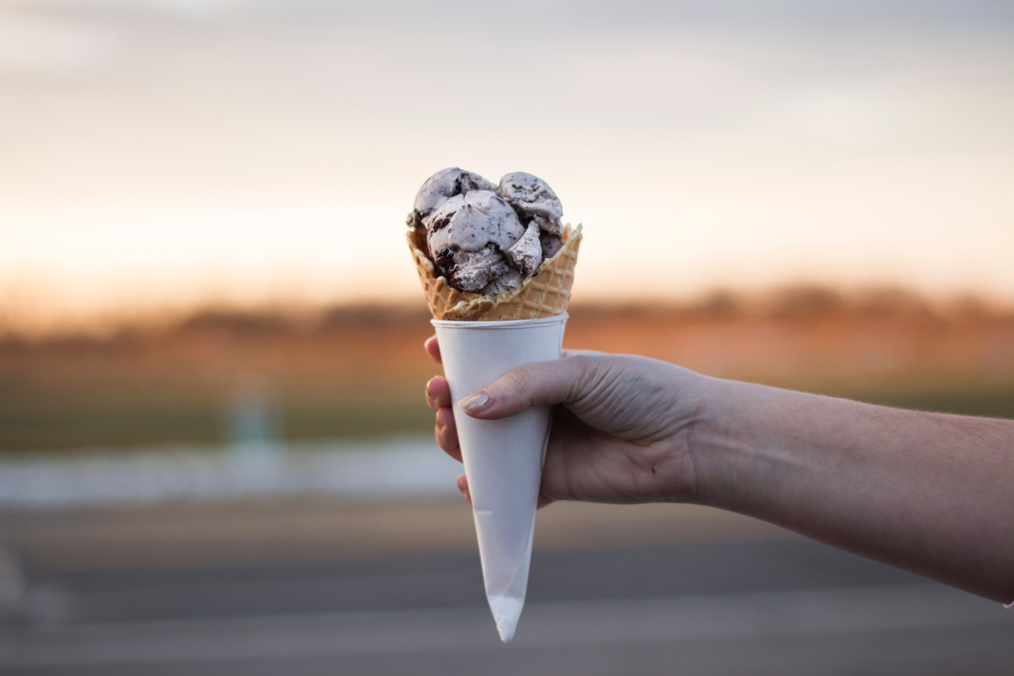 Woman holding a wafer with 3 scoops of ice cream in the air